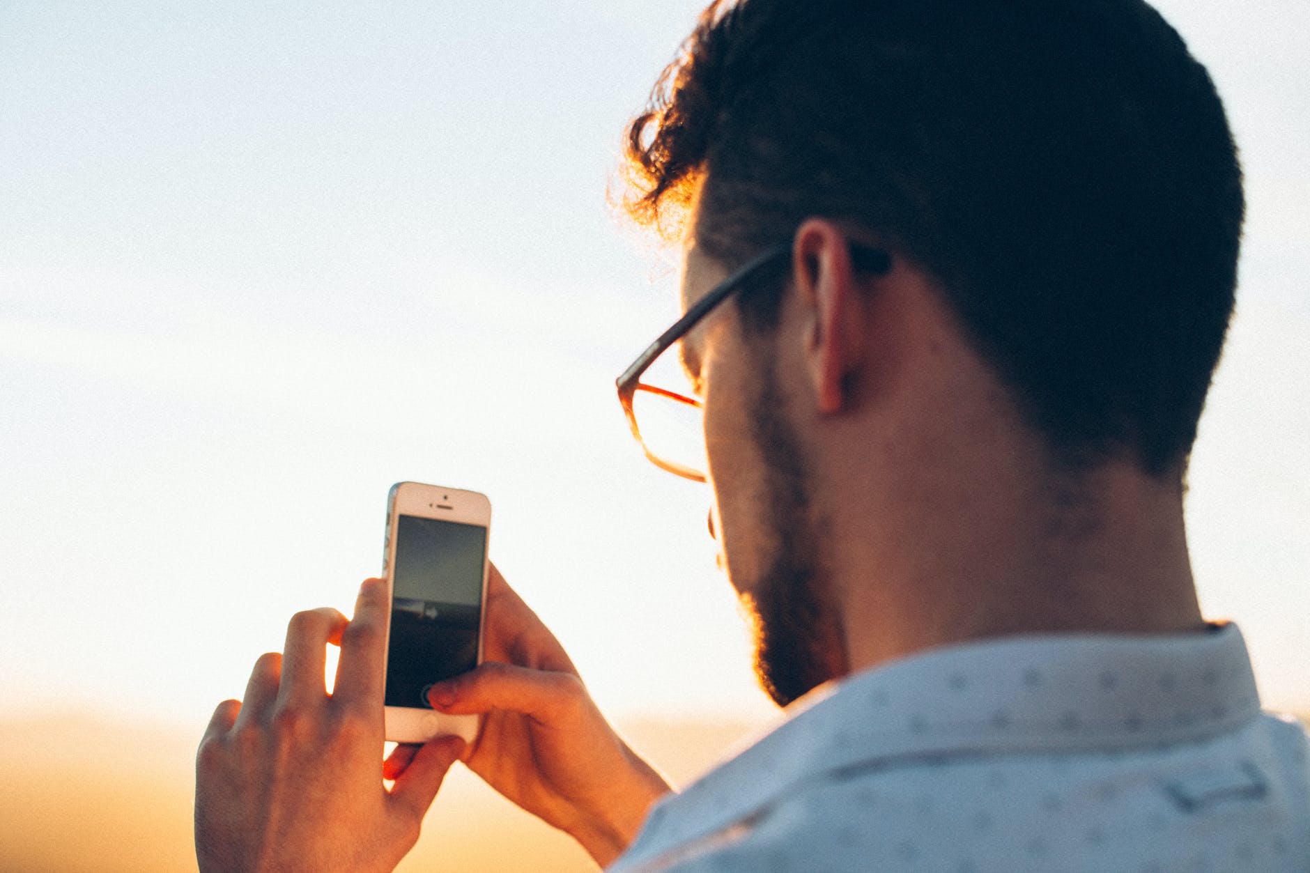 focused young man taking picture of morning scenery on smartphone