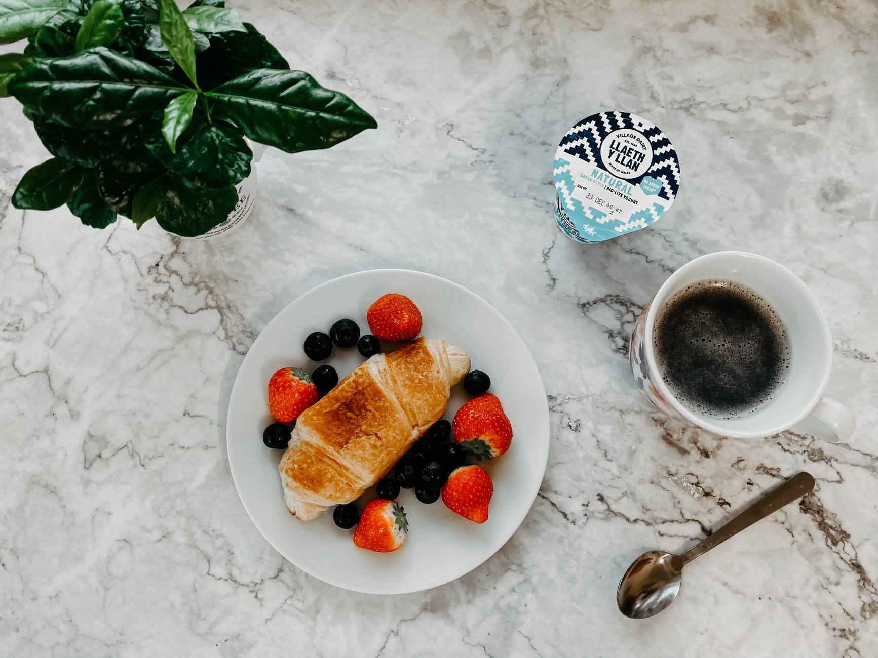 breakfast with berries and croissant with yogurt and coffee