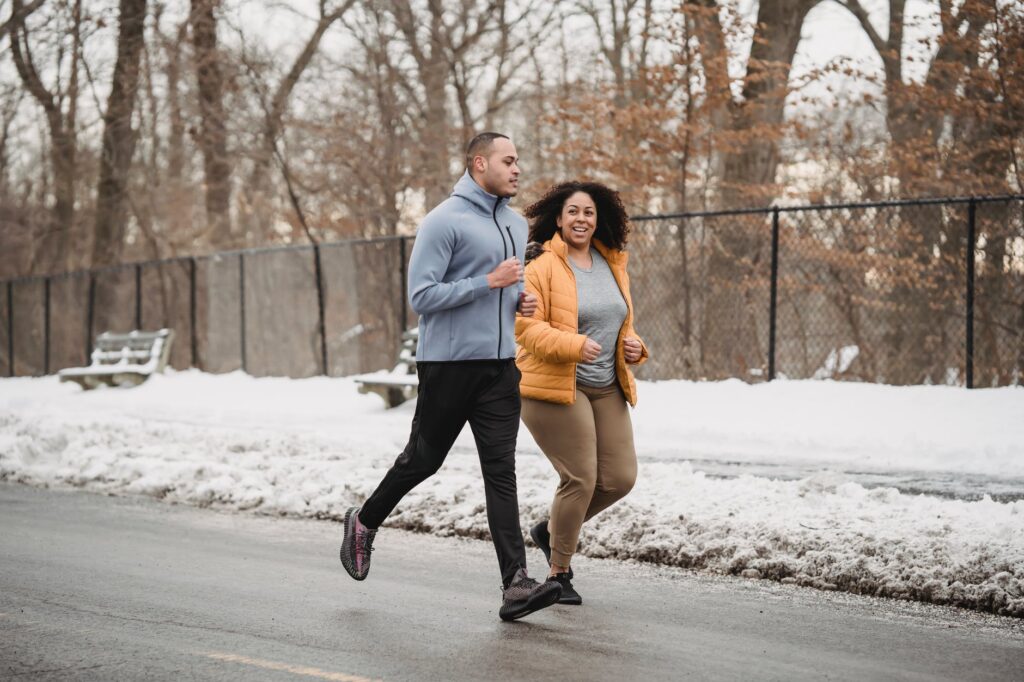 ethnic trainer and woman jogging on snowy street