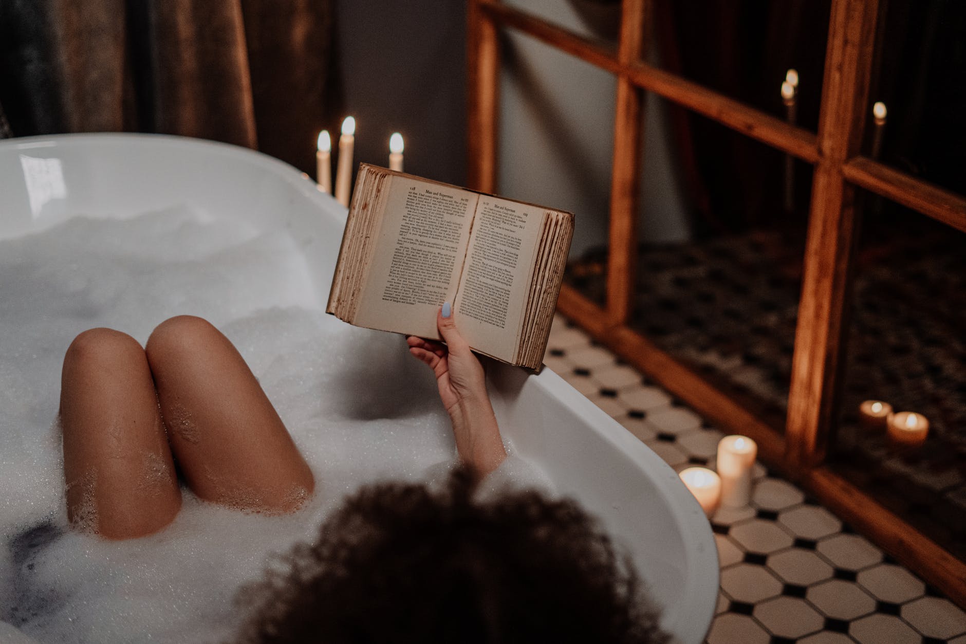 person reading book on bathtub