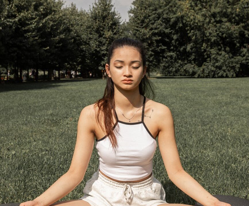 flexible woman practicing yoga in park