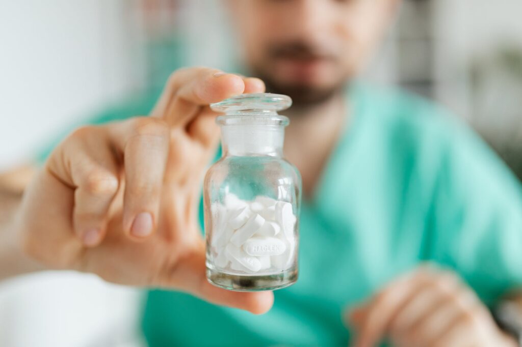 doctor demonstrates vial of white pills