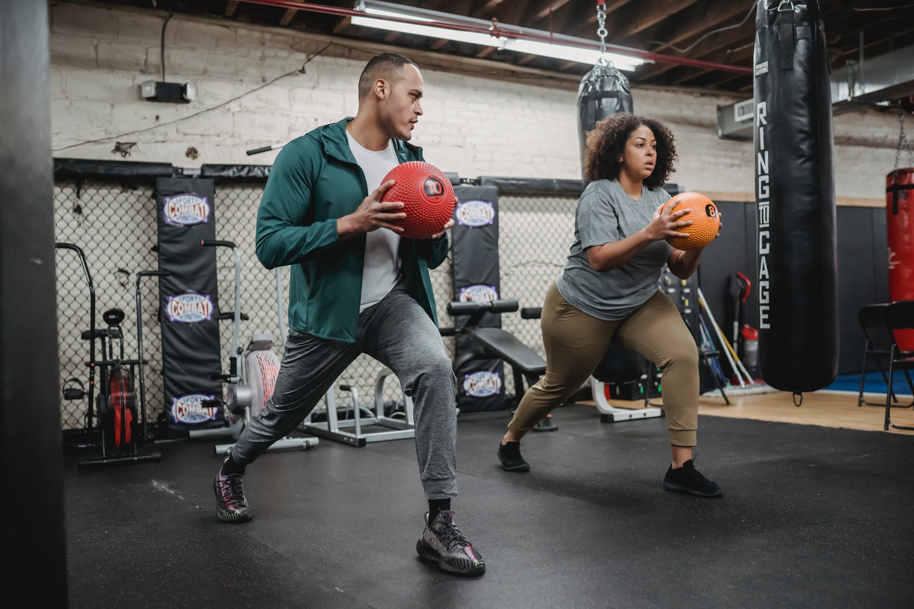 trainer and black woman exercising together in gym