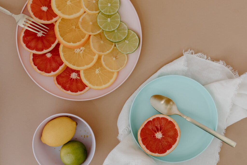 plates with sliced citrus fruits with cutlery near bowl