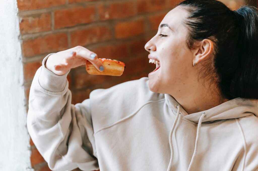 crop excited woman eating fresh yummy donut